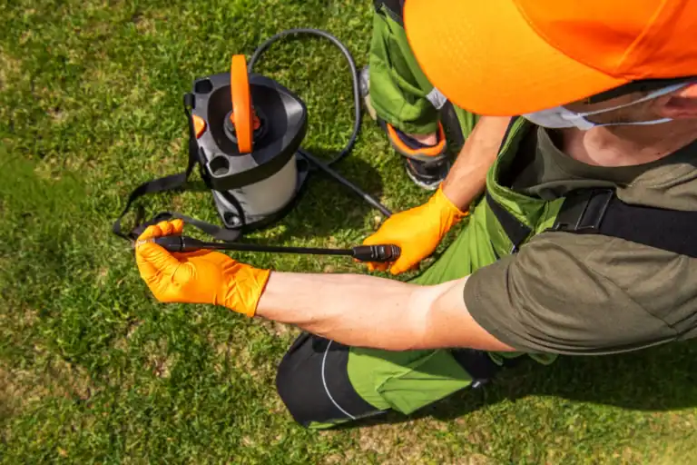 Persona che utilizza uno spruzzatore in giardino con attrezzatura verde e arancione.