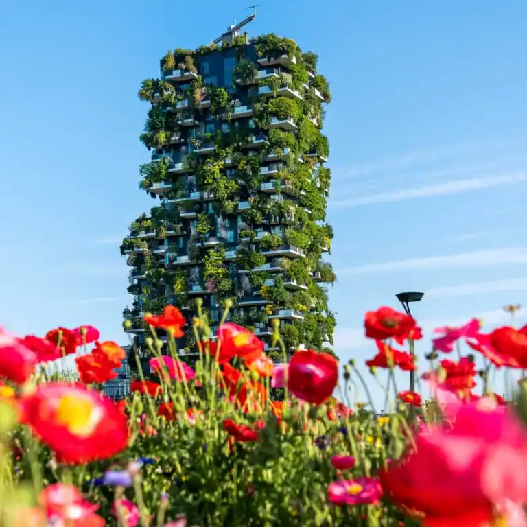 Edificio moderno con pareti verdi e piante in terrazza, simbolo di sostenibilità.
